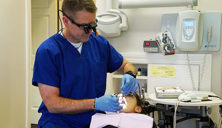 Dentist examining a boy's mouth at Dodge City Dental Care