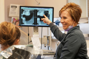 Dental hygienist showing mouth x rays to young girl at Dodge City Dental Care